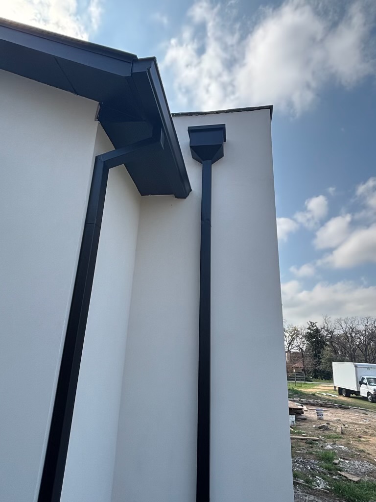 Matte black seamless gutters on a modern stucco home